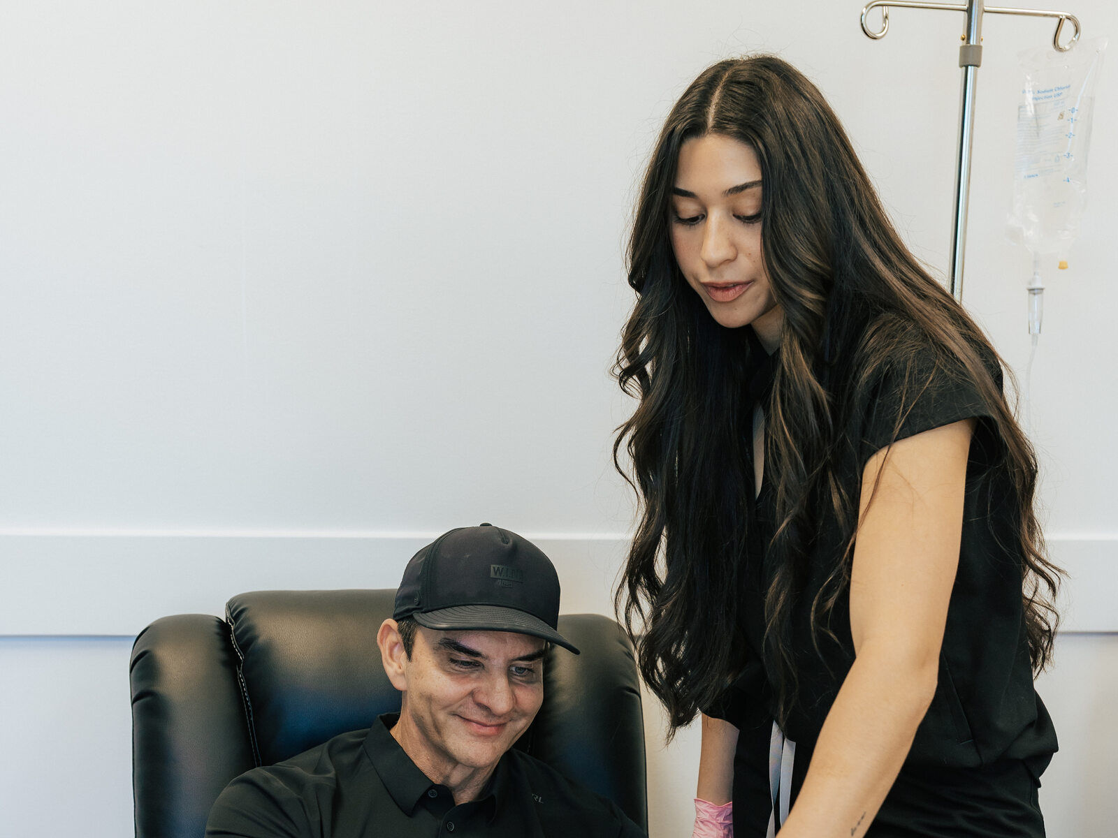 A clinician stands beside a seated visitor during a clinic visit.
