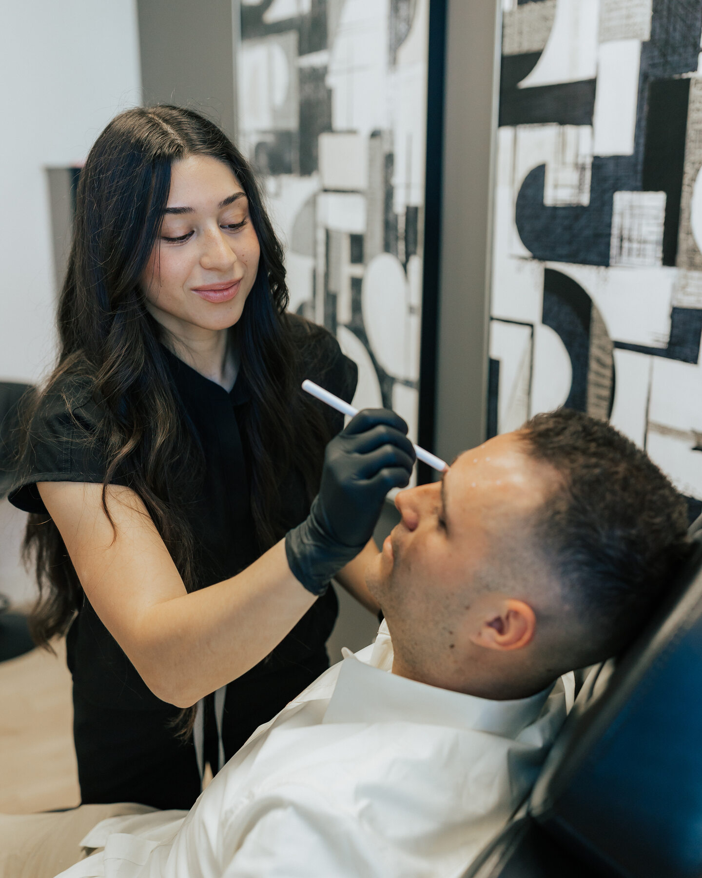 A clinician attends to a reclining visitor during an aesthetic treatment.